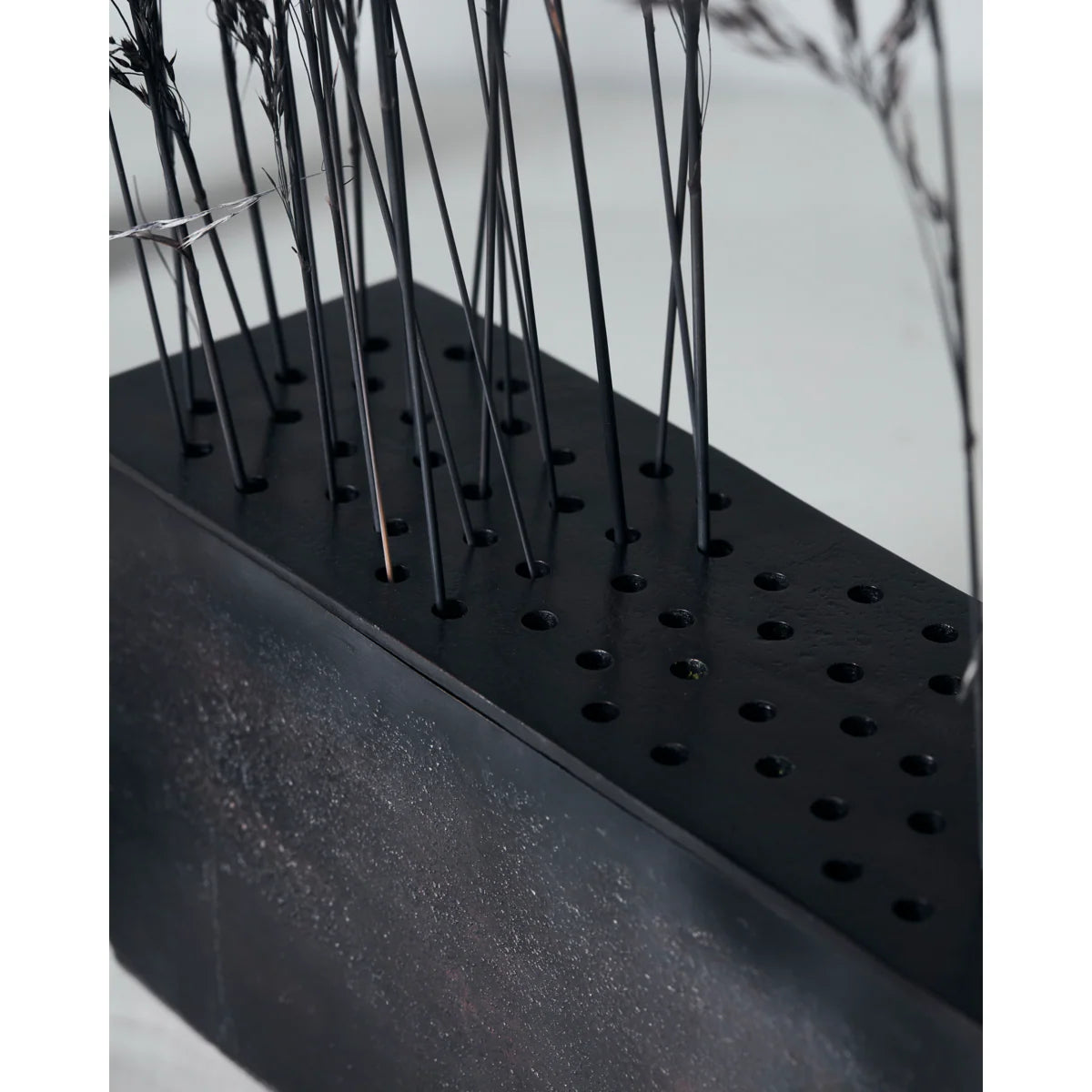 Black rectangular metal vase with small holes to put individual stems in