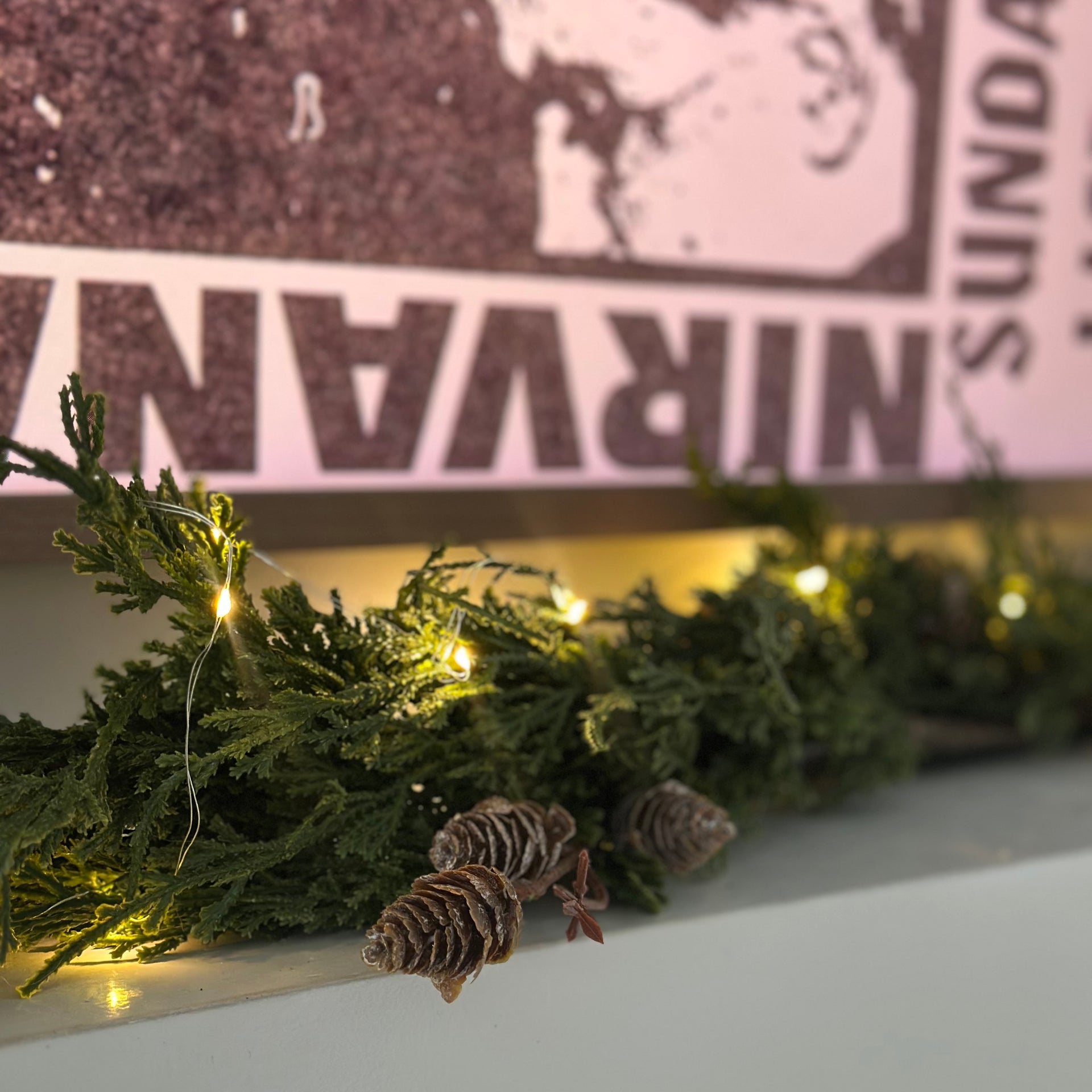 String lights on a Christmas wreath with a blurred Nirvana album cover in the background