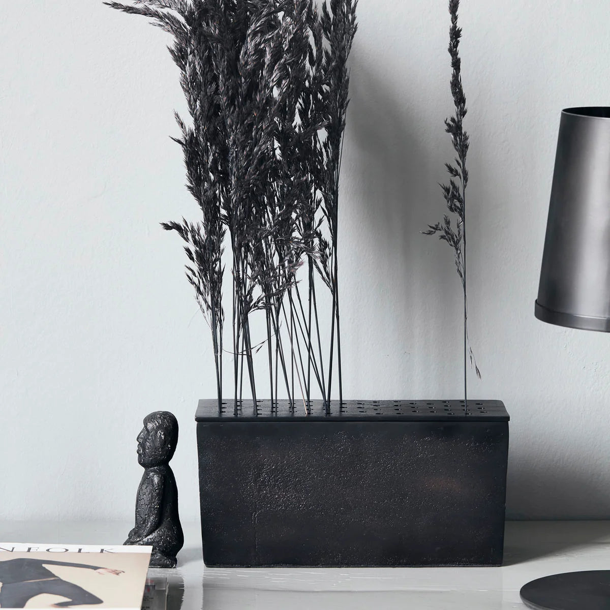 Decorative black metal vase with dried plants 